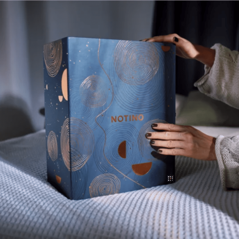 Explore the Notino Luxury Advent Calendar 2023, a daily delight for beauty enthusiasts. Unbox 25 treasures in a beautifully designed dark blue box with copper circle illustrations, featuring opulent beauty products throughout the holiday season.