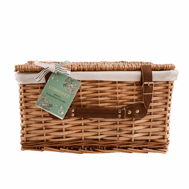 Cowshed Advent Calendar 2025 in a wicker hamper with 24 beauty treats from candles to lotions for festive self-care.