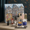 Luxurious Liberty London Beauty Advent Calendar 2025, illustrated in the shape of the iconic Tudor storefront, featuring high-end skincare, makeup, and fragrance products from brands like Le Labo, Augustinus Bader, and Sisley.