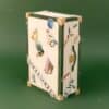 Vogue Festive Calendar 2026 Art Deco trunk closed, three-quarter angle showing the VOGUE ribbon on the lid