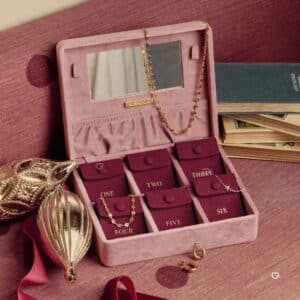 Missoma jewellery advent calendar 2026 open velvet case showing six numbered pouches and a gold necklace in a festive setting