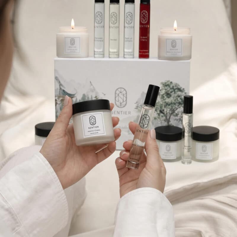 Holding a Sentier candle and perfume from the 2026 home fragrance calendar