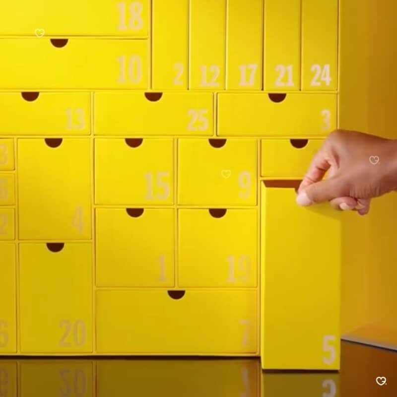 Yellow numbered drawers of the Selfridges Advent Calendar 2026, a hand opening a door