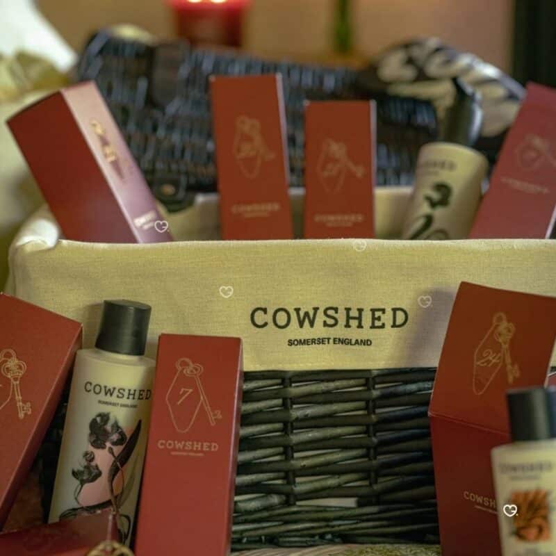 Close-up of numbered Cowshed Advent Calendar 2026 gift boxes inside the woven hamper in warm light