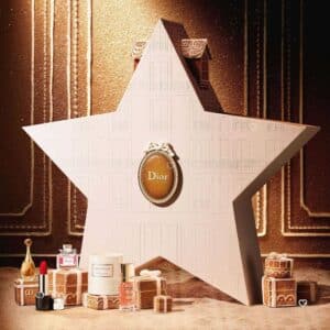 Dior Advent Calendar 2026, closed white star-shaped box with the Dior medallion, on a gold festive backdrop with beauty products