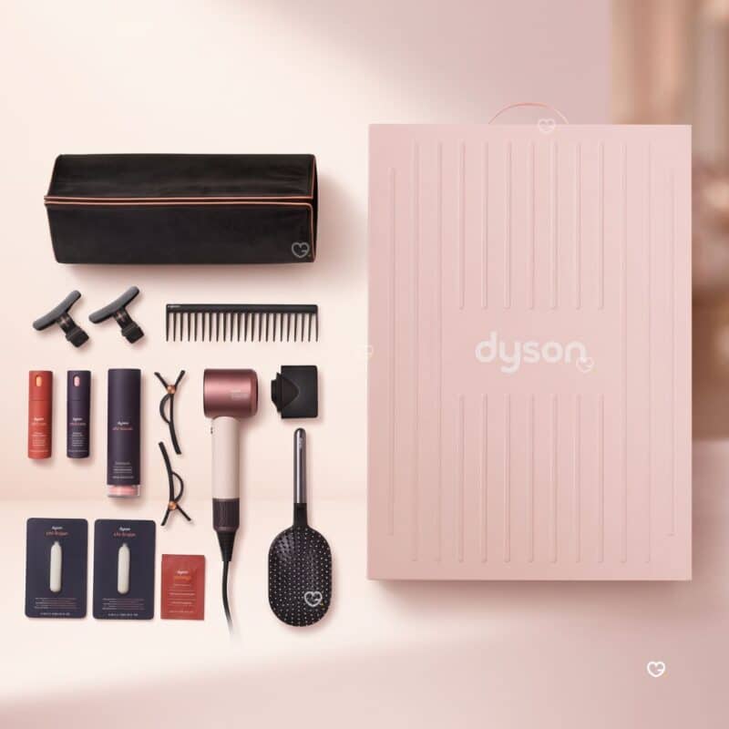 Dyson Advent Calendar 2026 full contents flat lay: storage bag, hair clips, comb, Chitosan and Omega sprays, Supersonic Travel dryer, paddle brush and samples