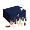 The 25 creations of the Guerlain Advent Calendar 2026 laid out beside the velvet box: fragrances, Abeille Royale skincare, Terracotta blush and Noir G mascara