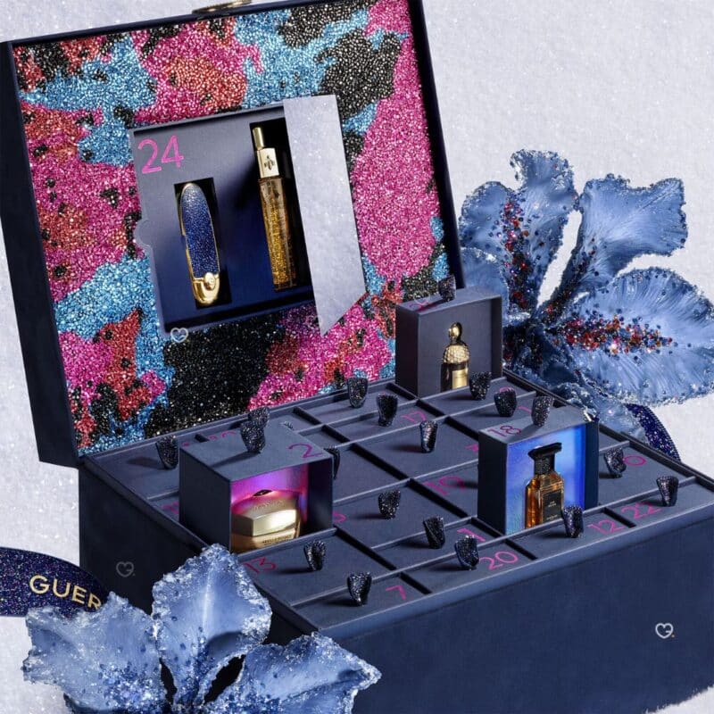Guerlain Advent Calendar 2026 open in a wintry setting, door 24 with a Rouge G lipstick and a fragrance behind the mirror