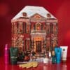 Rituals Advent Calendar 2026 townhouse box with body products and gold scrub gloves on a red background